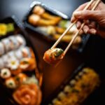 Food Aesthetics - Close-up of a hand holding sushi with chopsticks #30222105